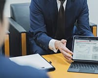 スーツ姿の男性がPCを指している手元の様子